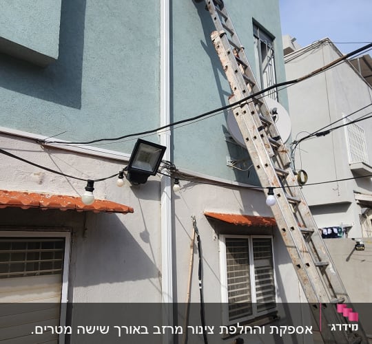 אדם על סולם מתקין מרזב על קיר חיצוני